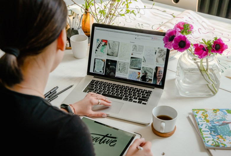 a woman sits at her laptop looking for design inspiration 