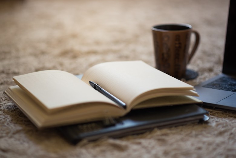 an open journal and laptop as a scene of a daily journaling practice