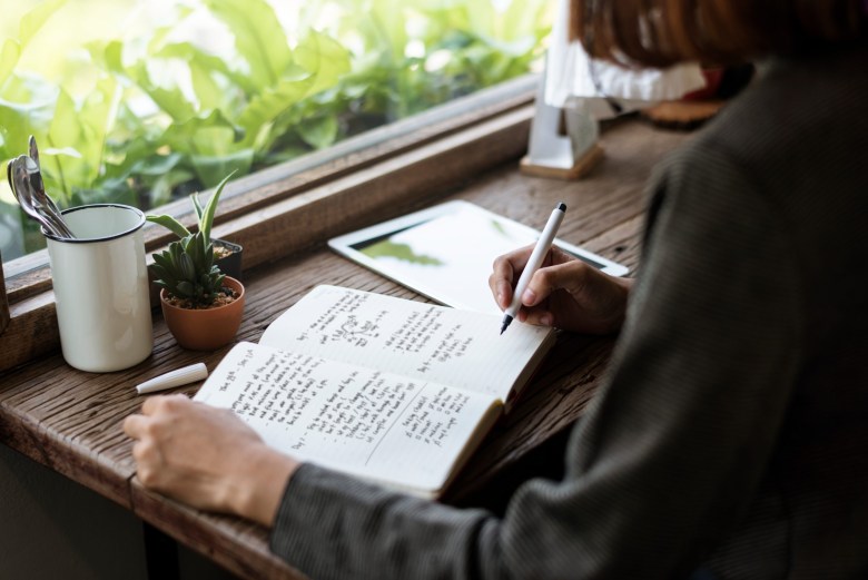 Closeup of girl writing on her journal as a way to practice daily reflections