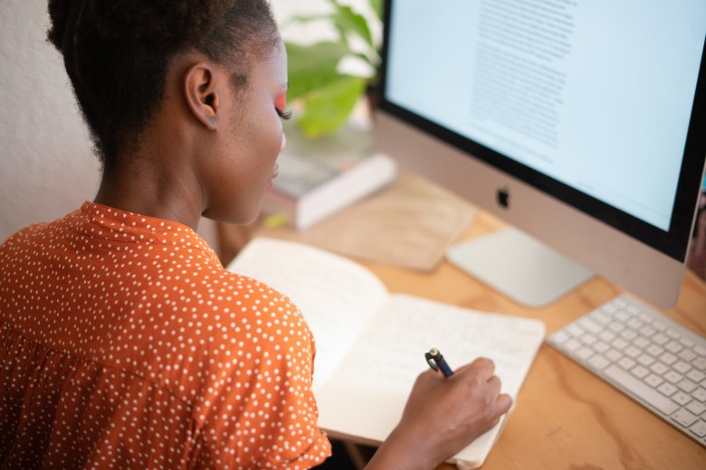 A woman writing in her gratitude journal on her desk in the morning.