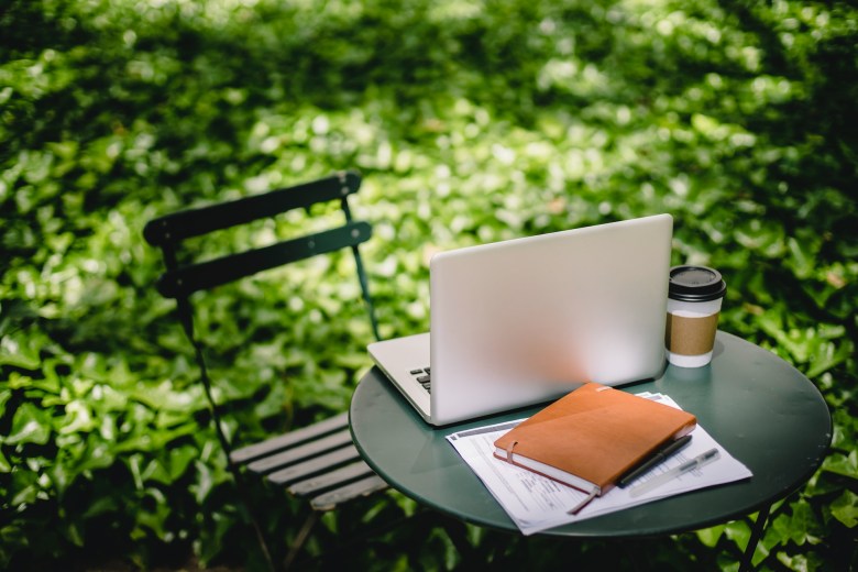 a scene of keeping a gratitude journal outdoors, along with a computer and coffee.