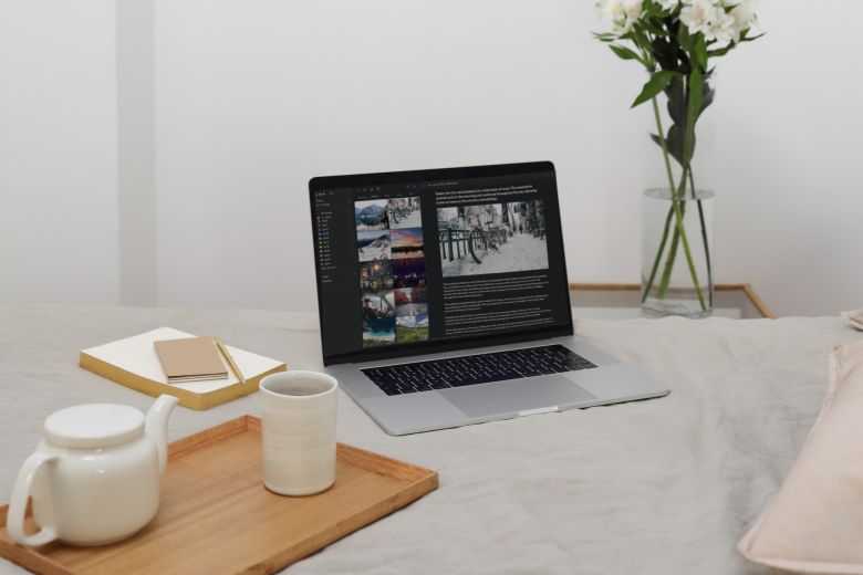 A scene of journaling on computer with notebook and tea. 