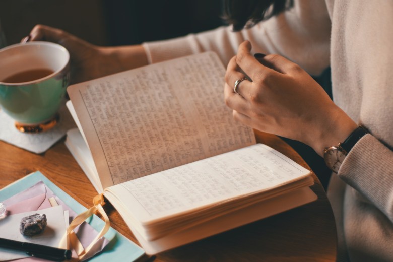 a person hold open a notebook and a cup of tea while journaling for depression