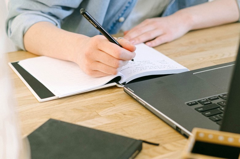 a woman answers journaling prompts for self-discovery next to her computer