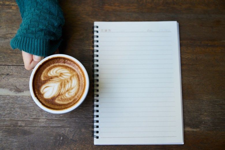 A person journaling in a notebook with a latte nearby as a form of dealing with stress and anxiety