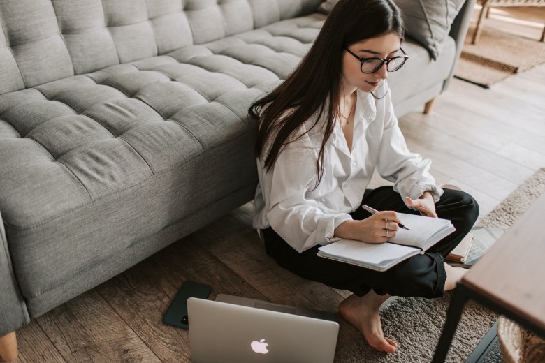 A person uses a notebook and laptop computer as their self-care journal