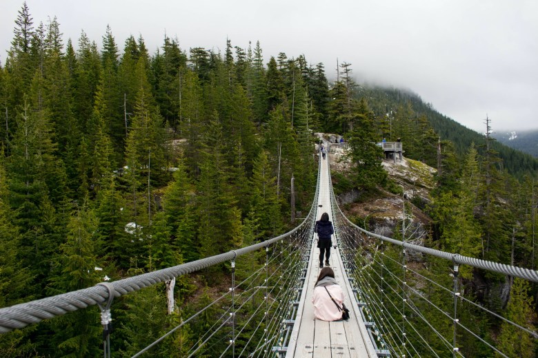 a woman sits on a bridge with her travel journal