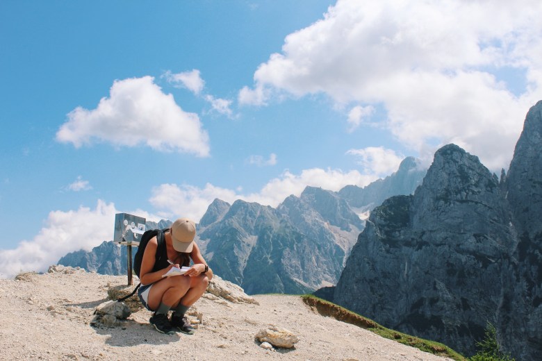 A woman stops to write about a view in her travel journal 