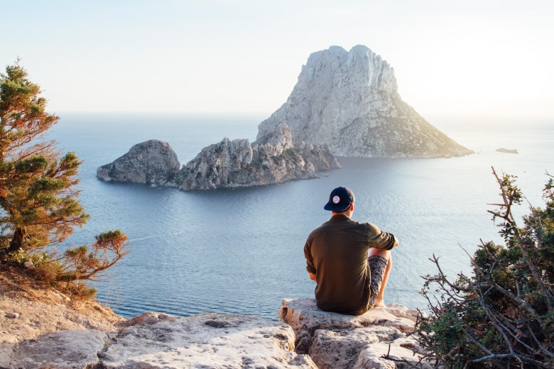 A person sits on an overlooking writing in a travel journal